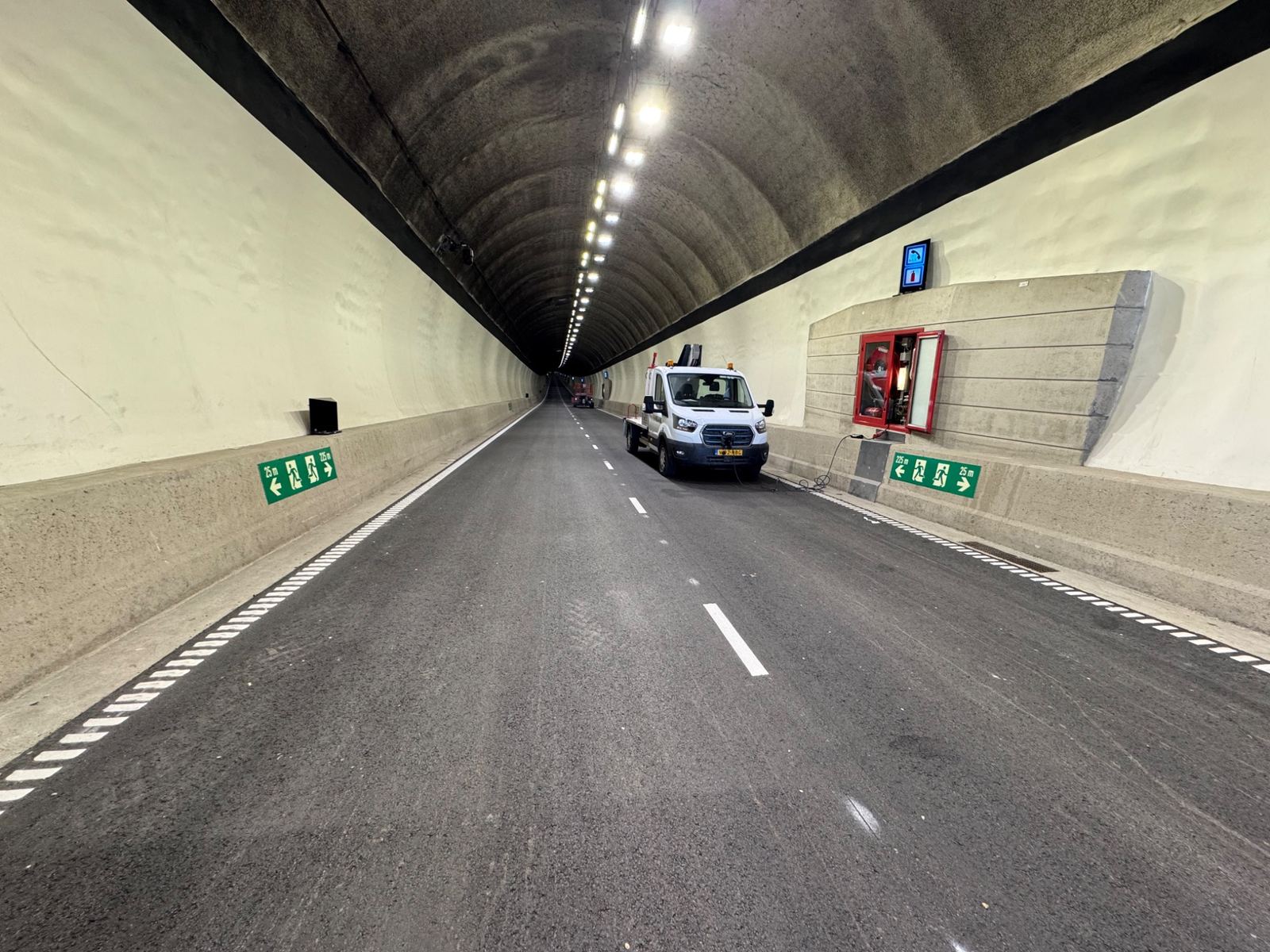 Tunnelbuis met verlichting, vluchtwegaanduiding en een hoogwerker